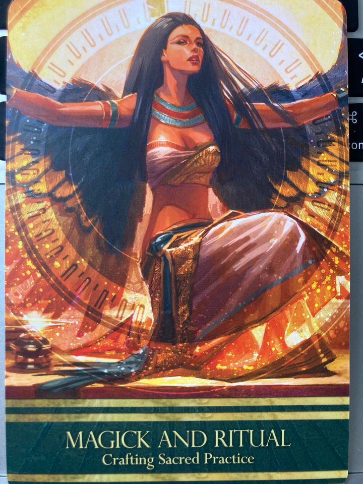 The goddess Isis, with long black hair and golden wings, kneels. Captioned Magick and Ritual: Crafting Sacred Practice