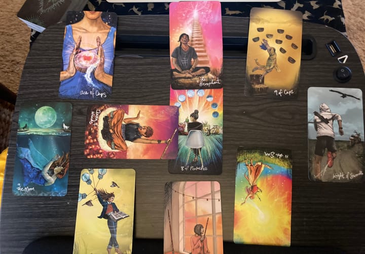 8 tarot cards laid in a circle with two cards across each other in the center.