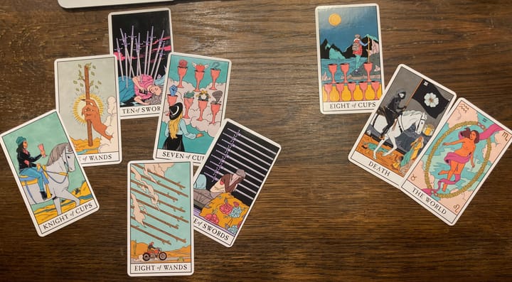 Nine tarot cards are spread out on a wooden table.